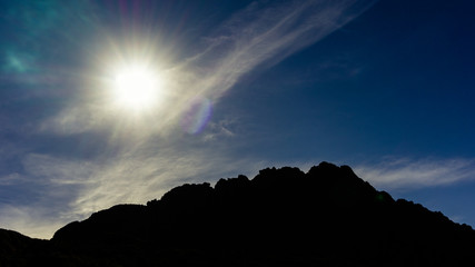 Silhouete of high mountain with blue sky and sun