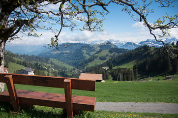 Brown wooden chair overlooking the swiss alps on mount rigi. Rest station with a view. Snow capped mountains