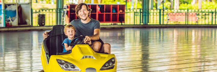 Father and son having a ride in the bumper car at the amusement park BANNER, long format