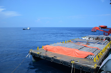 Concrete coated pipes are stacked and secured on cargo barge at offshore..