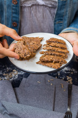 Woman hands holds dark rye bread slices. Homemade dark bread with coriander seeds on plate. Vegan vegetarian healthy food. Bread made of whole grains on dry frying pan. 