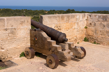 Fototapeta na wymiar Old antique iron cannon on the old defence tower of Punta de N'Amer near Sa Coma, on the Spanish Balearic Mediterranean island of Mallorca