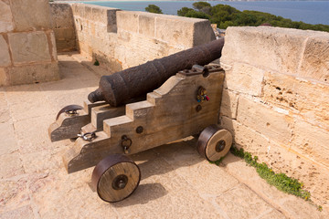 Fototapeta na wymiar Old antique iron cannon on the old defence tower of Punta de N'Amer near Sa Coma, on the Spanish Balearic Mediterranean island of Mallorca