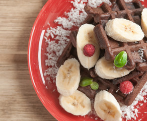 Viennese chocolate wafers with banana and raspberries. On a wooden background.
