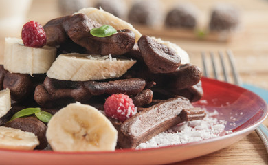 Viennese chocolate wafers with banana and raspberries. On a wooden background.