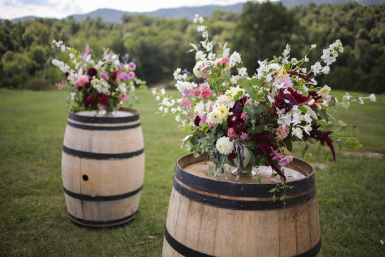 Vibrant Elegant Floral Arrangement Wedding Ceremony Decor with Pink, White Fuchsia, Purple, and Green Flowers on Wooden Wine Barrel Overlooking Mountains Outdoors