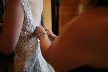 Wedding Photography: Mother Buttoning Up the Back of Bride's Lace Wedding Dress Helping Her Get Ready