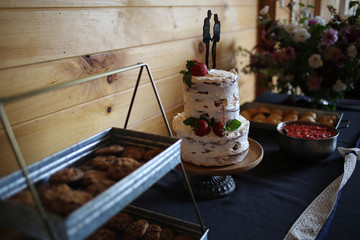 Delicious wedding reception dessert table with Wedding cake, chocolate chip cookies, and strawberry shortcake - Rustic wedding with wooden background and wildflowers