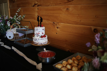 Delicious wedding reception dessert table with Wedding cake, chocolate chip cookies, and strawberry shortcake - Rustic wedding with wooden background and wildflowers