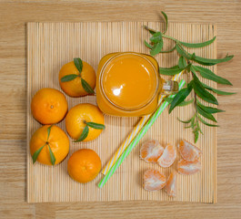 Still life. A transparent mug with a handle with freshly squeezed tangerine juice. And fresh tangerines. 
