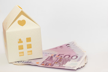 paper model toy house on top of 500 euro banknotes. conceptual image of buying, selling, saving, loan for a house.
