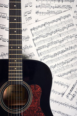 Fototapeta na wymiar dark acoustic guitar on a background sheet notes, close-up