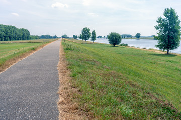 Fototapeta na wymiar Long bike path along a wide Dutch river