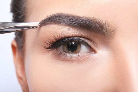 Young woman correcting eyebrow shape, closeup