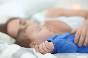 Mother with her baby sleeping on bed at home