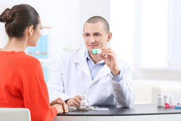 Male doctor showing contact lens case to patient in hospital
