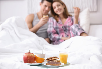 Tray with yummy breakfast for young couple in bed