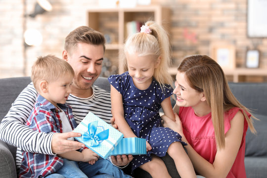 Happy family with little children opening gift box at home