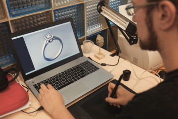 Jewelry designer working on laptop, closeup