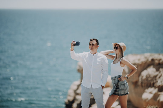 Happy young couple in love taking selfie with mobile phone on beach