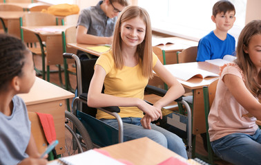 Teenage girl in wheelchair with classmates at school