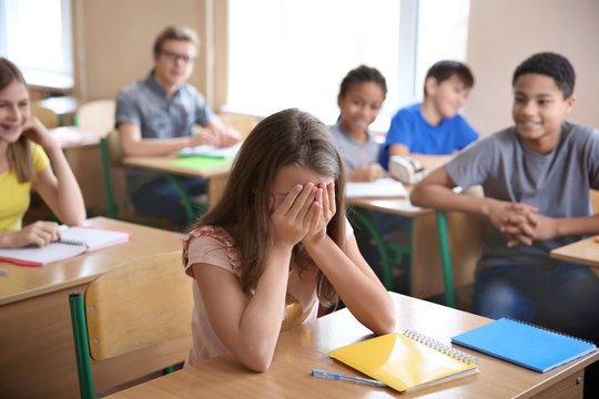 Sad girl sitting in classroom. Bullying at school