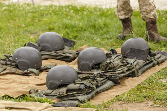 Camouflage combat flak jackets and helmets lined up on the ground