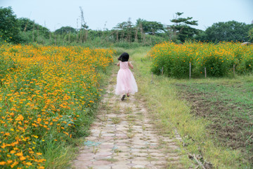 Little girl wearing pink skirt running on daisy flower field