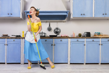 Retro / pin up girl woman female / housewife wearing colorful top, skirt and white apron holding...