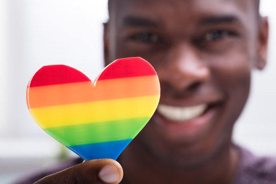 Smiling Man Holding Rainbow Heart In His Hand