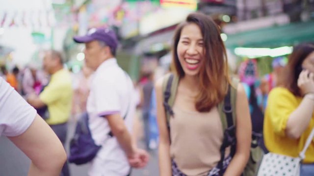 Slow motion - Traveler backpacker asian woman travel in Khao San road at Bangkok, Thailand. Happy young female spending holiday trip at amazing landmark and enjoy her journey in traditional city.