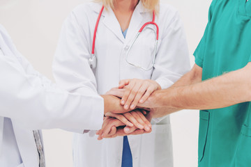 Doctor, surgeon and nurse join hands together.