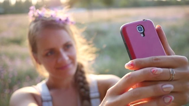 Make photo - young lady taking selfie picture via smart phone on nature sunset