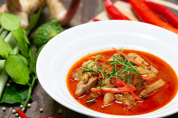 Chicken panang curry in the white bowl and fresh spice on brown wooden background Thai food