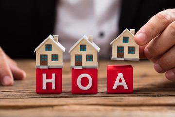 Businessperson placing house model over HOA blocks
