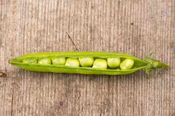 fresh open pod of green peas from the garden on a wooden background