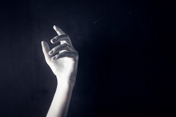 White painted hand on a black background. Abstract. Copy space