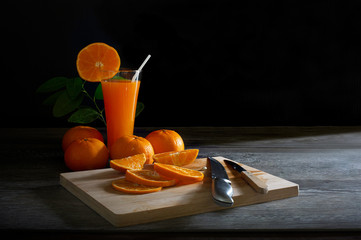 Fresh oranges and oranges juice in glass with pieces oranges on the chopping wood  and wooden floor...