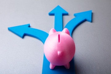 Elevated View Of Pink Piggybank And Blue Arrow Signs