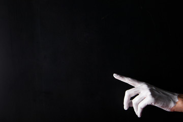 White painted hand on a black background. Abstract. Copy space