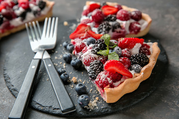 Slate plate with pieces of delicious berry pie on table