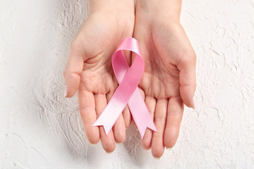 Woman holding pink ribbon on light background. Breast cancer awareness concept