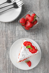 Plate with piece of delicious strawberry cake on wooden table, top view