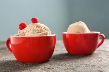 Tasty ice-cream with raspberries in cups on table