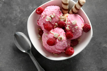 Bowl with tasty raspberry ice-cream on grey table