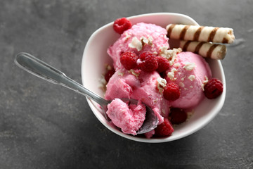 Bowl with tasty raspberry ice-cream on grey table