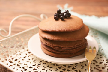 Plate with tasty chocolate pancakes and berries on tray, closeup