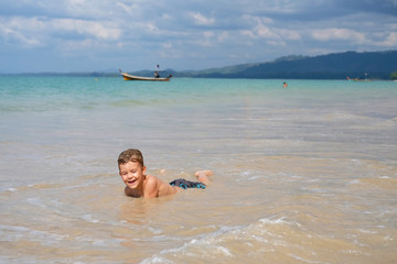 Boy 6 years old lies in waves of Andaman Sea, Thailand