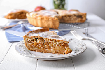 Plate with piece of tasty apple pie on table