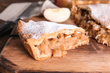 Piece of tasty apple pie on wooden board